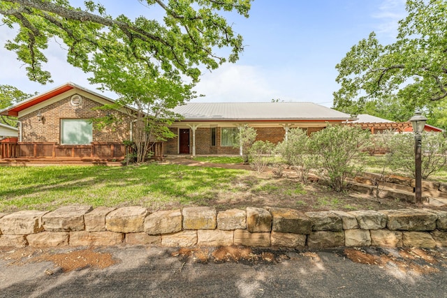 view of front of home with metal roof, a front yard, and brick siding