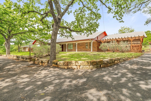 view of front of home featuring metal roof, a front lawn, covered porch, and brick siding