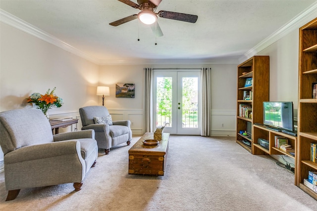 living area featuring ornamental molding, french doors, carpet floors, a ceiling fan, and a decorative wall