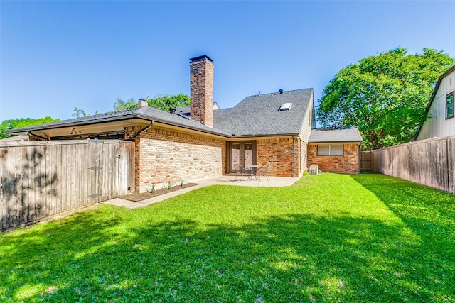 back of house featuring brick siding, a chimney, a patio, and roof with shingles