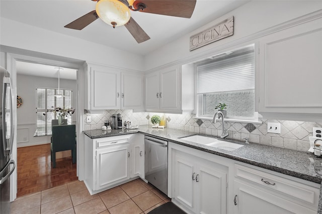 kitchen with a sink, stainless steel appliances, dark stone countertops, and white cabinetry