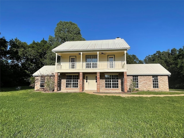 view of front of property with a front yard, metal roof, and a balcony