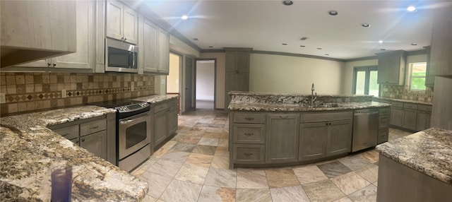 kitchen featuring crown molding, appliances with stainless steel finishes, and stone counters