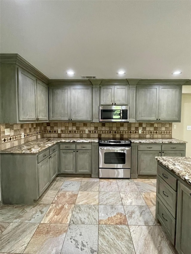 kitchen featuring light stone countertops, stainless steel appliances, gray cabinetry, tasteful backsplash, and visible vents