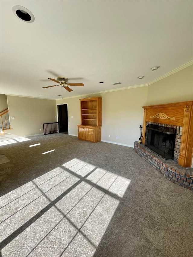 unfurnished living room featuring a ceiling fan, crown molding, a brick fireplace, baseboards, and carpet flooring