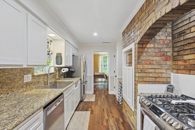 kitchen featuring light stone counters, stainless steel appliances, white cabinets, ornamental molding, and a sink