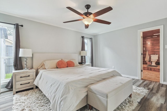 bedroom with ceiling fan, ensuite bath, baseboards, ornamental molding, and wood finished floors
