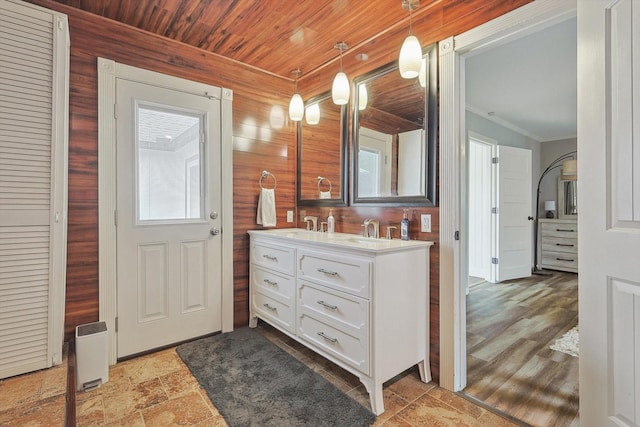 full bath featuring double vanity, wood ceiling, ornamental molding, and a sink