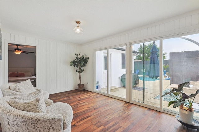 living area featuring wood finished floors, ceiling fan, and baseboards