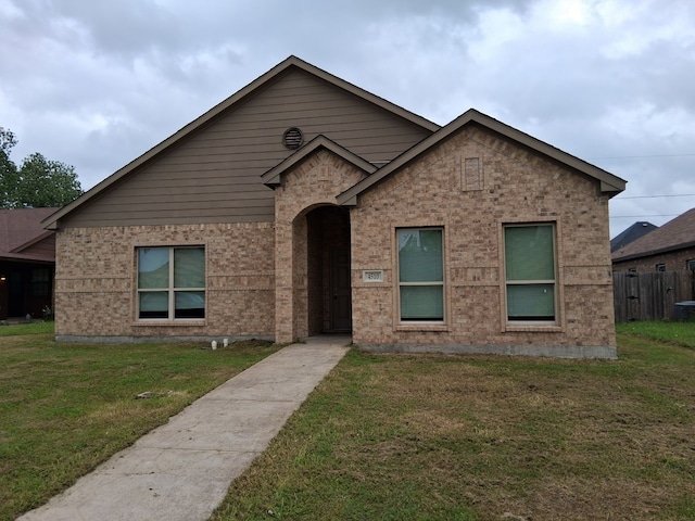 view of front of home featuring brick siding, fence, and a front yard
