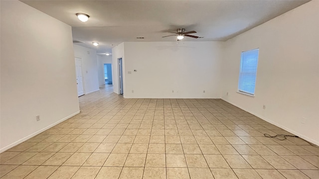 empty room with light tile patterned flooring, a ceiling fan, and baseboards