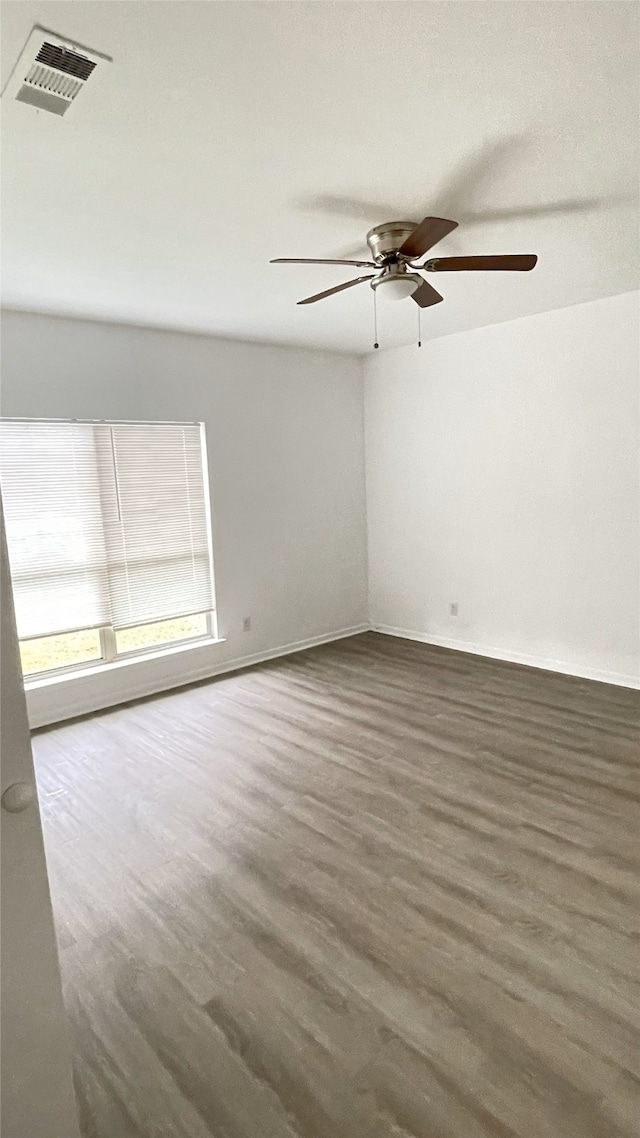 empty room featuring wood finished floors, visible vents, a ceiling fan, and baseboards