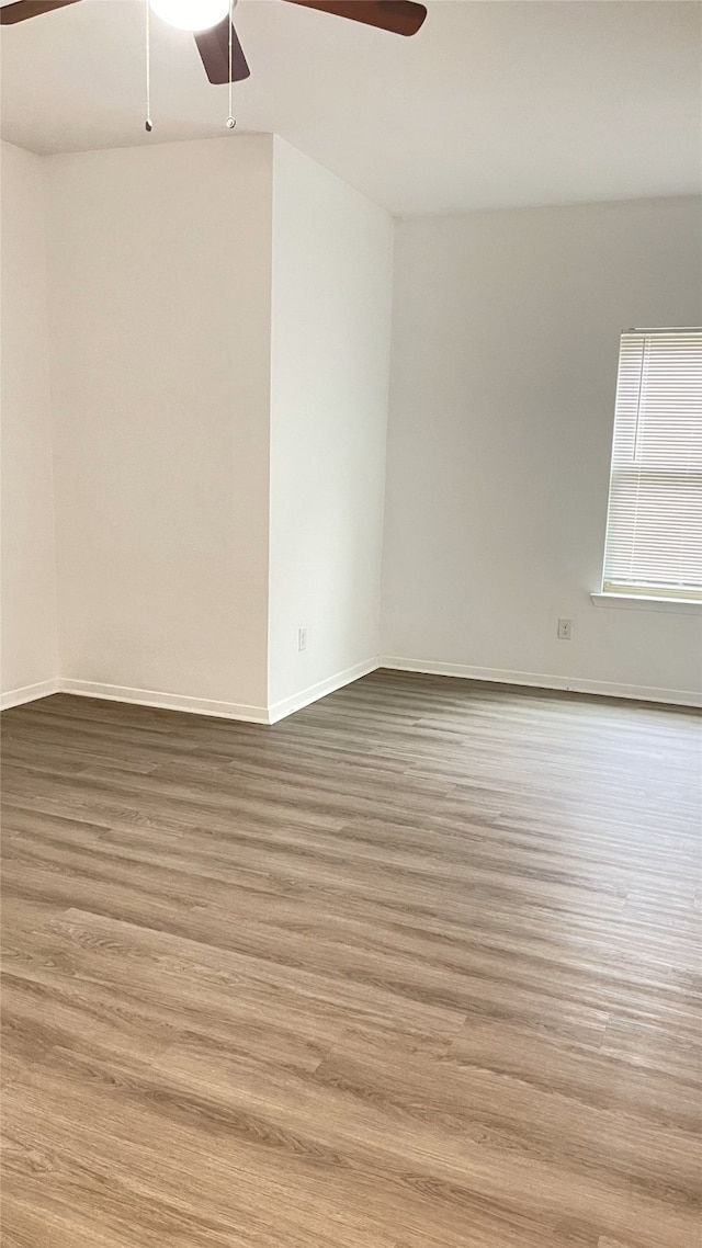 empty room with baseboards, wood finished floors, and ceiling fan
