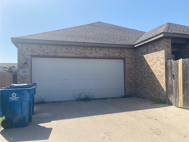 garage featuring driveway and fence