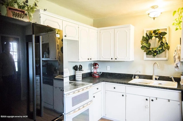 509 W 3rd St, Claude, TX 79019 - kitchen with a sink, range with two ovens, white cabinetry, dark countertops, and freestanding refrigerator