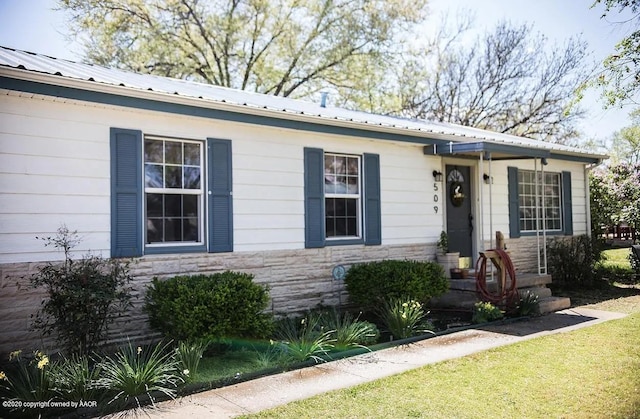 509 W 3rd St, Claude, TX 79019 - view of front of house with a front lawn, metal roof, and stone siding