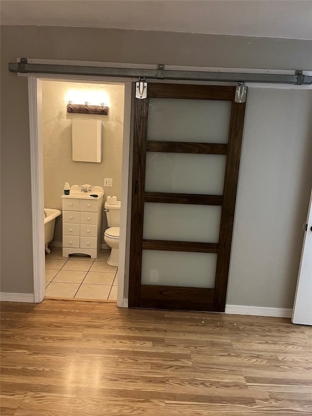 509 W 3rd St, Claude, TX 79019 - bathroom featuring baseboards, wood finished floors, toilet, and a sink