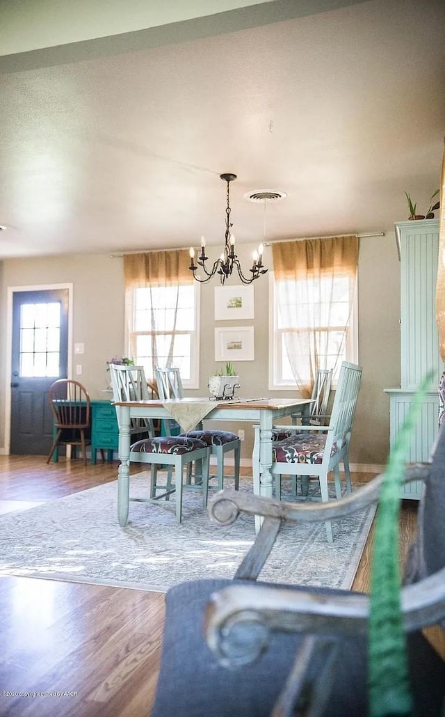 509 W 3rd St, Claude, TX 79019 - dining space featuring visible vents, wood finished floors, and an inviting chandelier