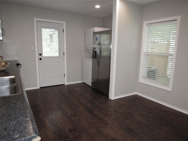 316 Tennessee St, Graham, TX 76450 - kitchen featuring stainless steel fridge, stacked washer and clothes dryer, dark wood-type flooring, baseboards, and dark countertops