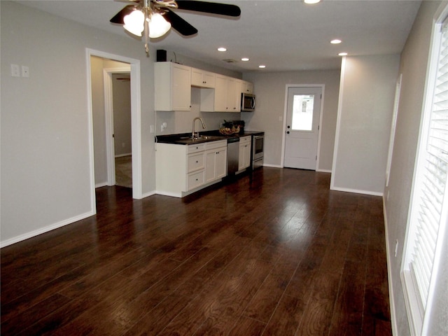 316 Tennessee St, Graham, TX 76450 - kitchen featuring dark wood-style flooring, ceiling fan, white cabinetry, dark countertops, and appliances with stainless steel finishes