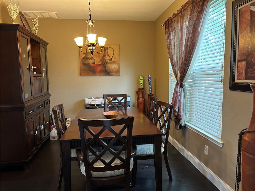 dining area featuring an inviting chandelier, baseboards, visible vents, and dark wood-style floors