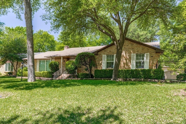 ranch-style house with a chimney, brick siding, fence, and a front lawn
