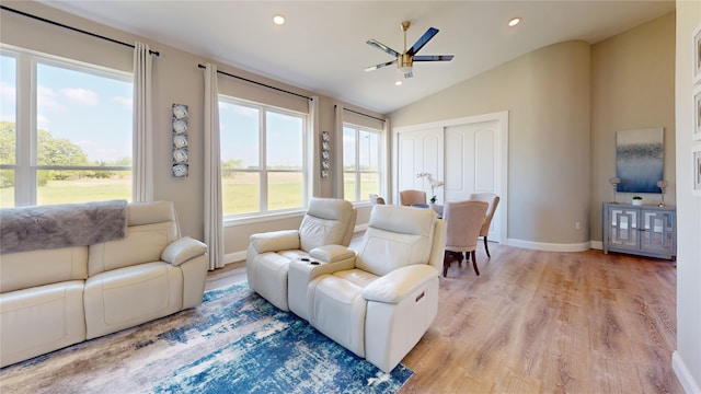 living room featuring baseboards, a ceiling fan, light wood-style floors, and lofted ceiling