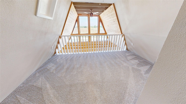 staircase featuring carpet and a textured wall