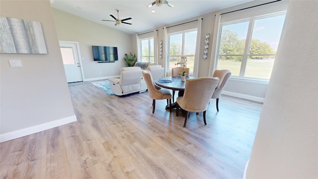 dining space featuring ceiling fan, light wood-style floors, lofted ceiling, and baseboards