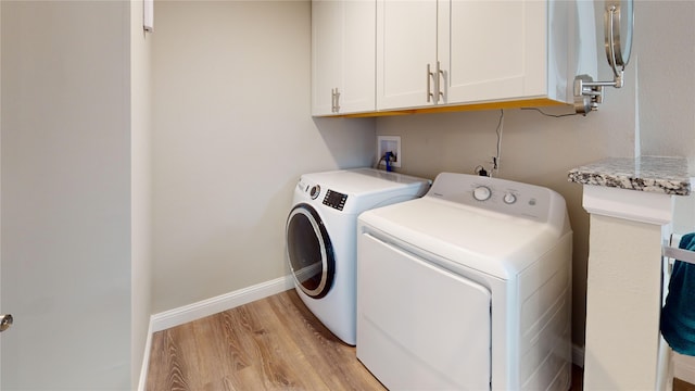laundry area with baseboards, cabinet space, washing machine and clothes dryer, and light wood-type flooring
