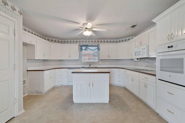 kitchen with white appliances, a textured ceiling, ceiling fan, and a sink