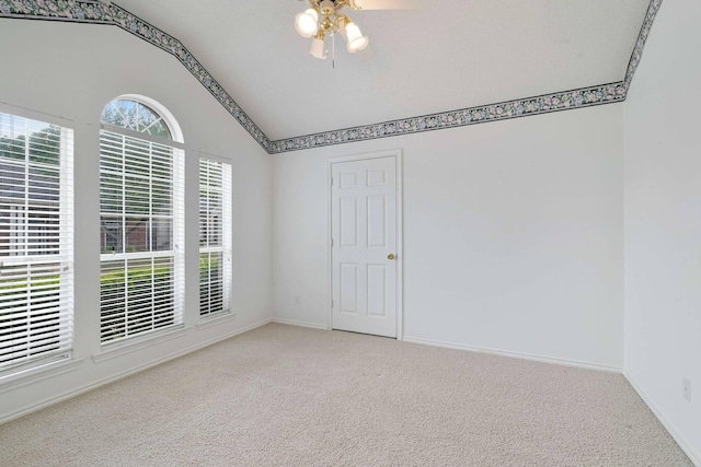 empty room featuring baseboards, ceiling fan, carpet, and lofted ceiling