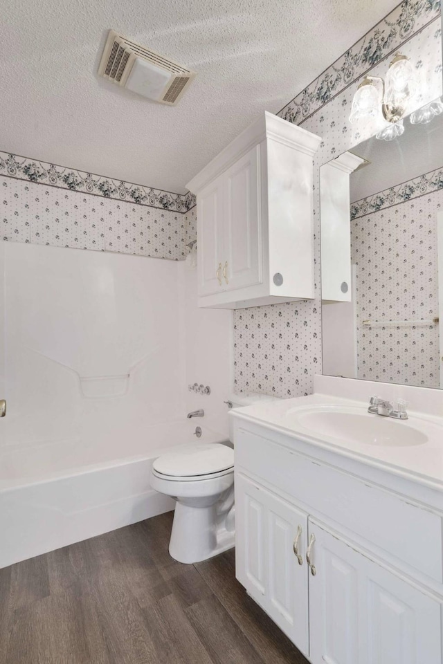 bathroom with visible vents, wallpapered walls, toilet, wood finished floors, and vanity
