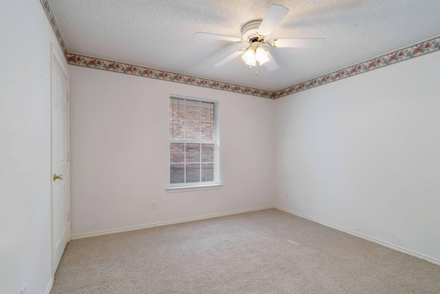 spare room with a textured ceiling, ceiling fan, baseboards, and light carpet