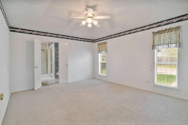 spare room with a wealth of natural light, a ceiling fan, and carpet flooring