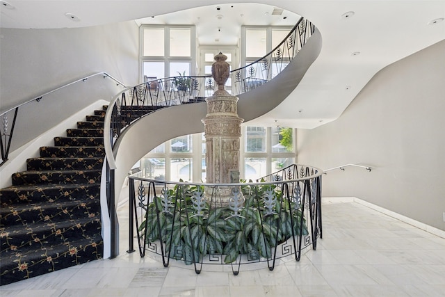 stairway with baseboards, arched walkways, and plenty of natural light