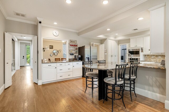 kitchen featuring visible vents, a peninsula, white cabinetry, and appliances with stainless steel finishes