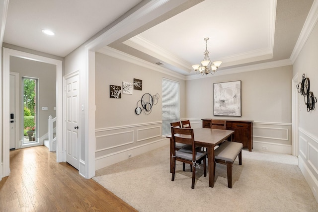 dining area with light wood-style floors, a notable chandelier, ornamental molding, and a decorative wall