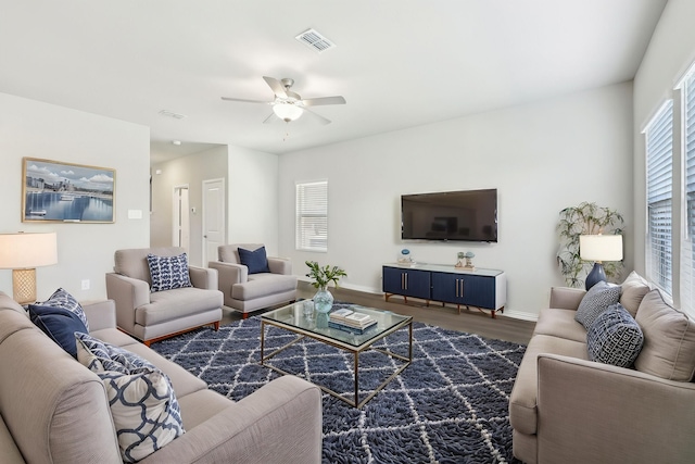 living area featuring visible vents, ceiling fan, dark wood-style floors, and baseboards