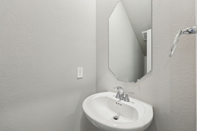bathroom featuring a sink and a textured wall