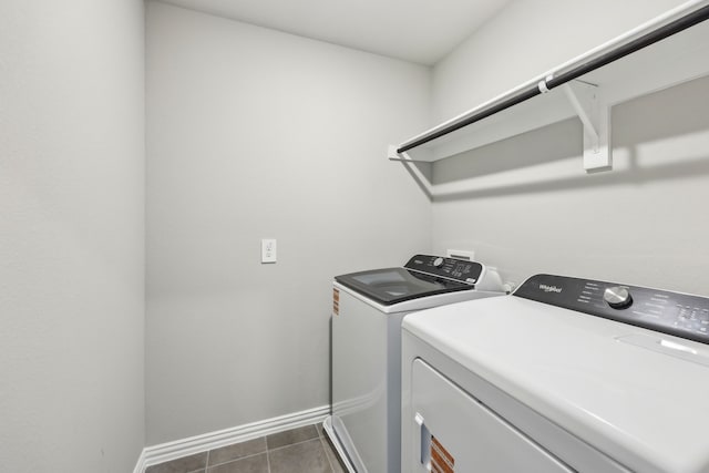 washroom with baseboards, washer and dryer, dark tile patterned flooring, and laundry area