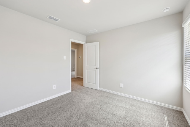 carpeted spare room featuring visible vents and baseboards