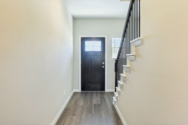 doorway with dark wood finished floors, stairway, and baseboards