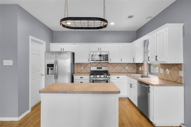 kitchen with a sink, stainless steel appliances, light wood-type flooring, visible vents, and white cabinets