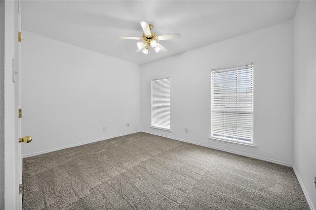 carpeted spare room with a healthy amount of sunlight, baseboards, and a ceiling fan