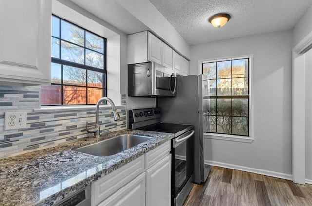 5316 Columbia Ave, Dallas, TX 75214 - kitchen featuring light stone countertops, a sink, stainless steel appliances, dark wood-type flooring, and white cabinetry