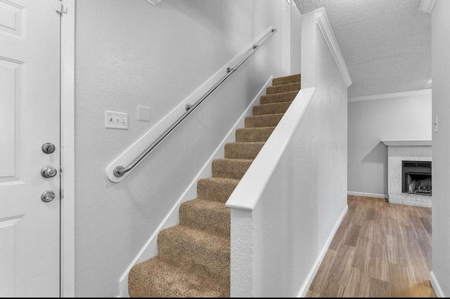5316 Columbia Ave, Dallas, TX 75214 - stairs with wood finished floors, ornamental molding, a fireplace, baseboards, and a textured ceiling