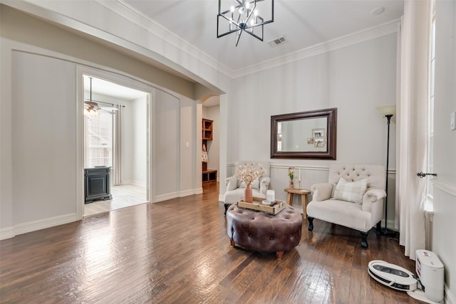 sitting room with visible vents, ornamental molding, wood-type flooring, baseboards, and a chandelier