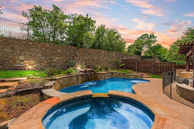 pool at dusk with a patio, fence, and a pool with connected hot tub