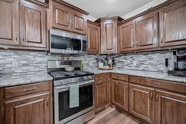 717 S Elm St, Sherman, TX 75090 - kitchen with light stone countertops, decorative backsplash, light wood-type flooring, ornamental molding, and appliances with stainless steel finishes